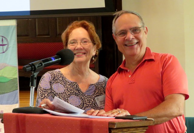 Woman and man standing in front of a podium smiling